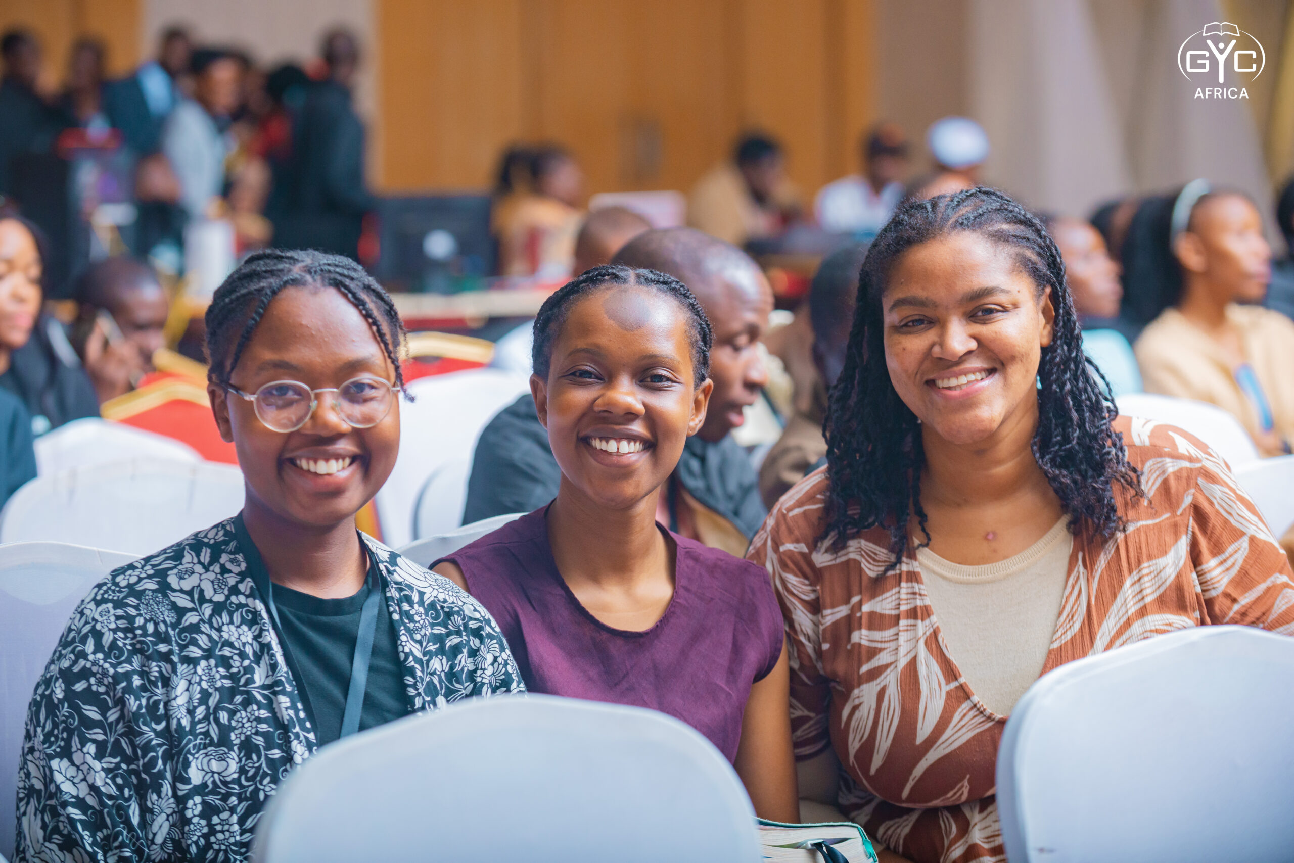 Three smiling delegates in the audience at GYC Africa 2026